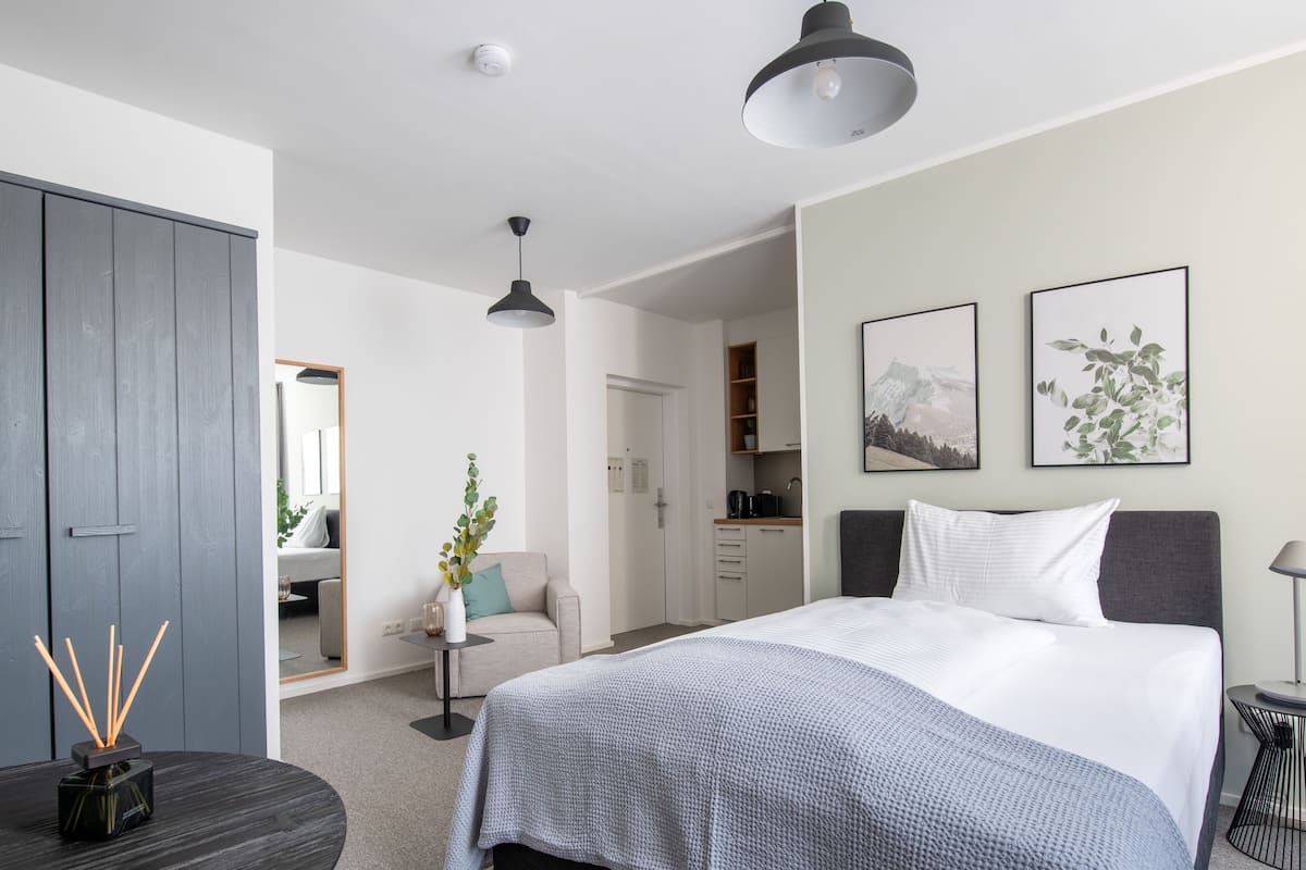 A modern bedroom with a bed, bedside tables, a desk, and a wardrobe.