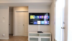 A living room with a flat-screen TV mounted on the wall displaying various streaming apps. - ★GORGEOUS STYLISH APT Close to American Dream & NYC★ (Belleville)