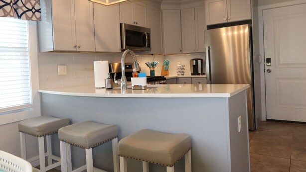 A modern kitchen with white cabinets, stainless steel appliances, and a central island with stools. - ★GORGEOUS STYLISH APT Close to American Dream & NYC★ (Belleville)