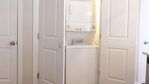 A laundry room with a washer and dryer, a sign above the dryer, and white doors. - ★GORGEOUS STYLISH APT Close to American Dream & NYC★ (Belleville)