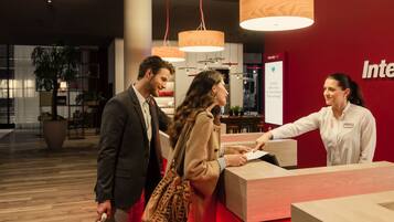 A reception area with a red wall, wooden reception desk, and hanging pendant lights.