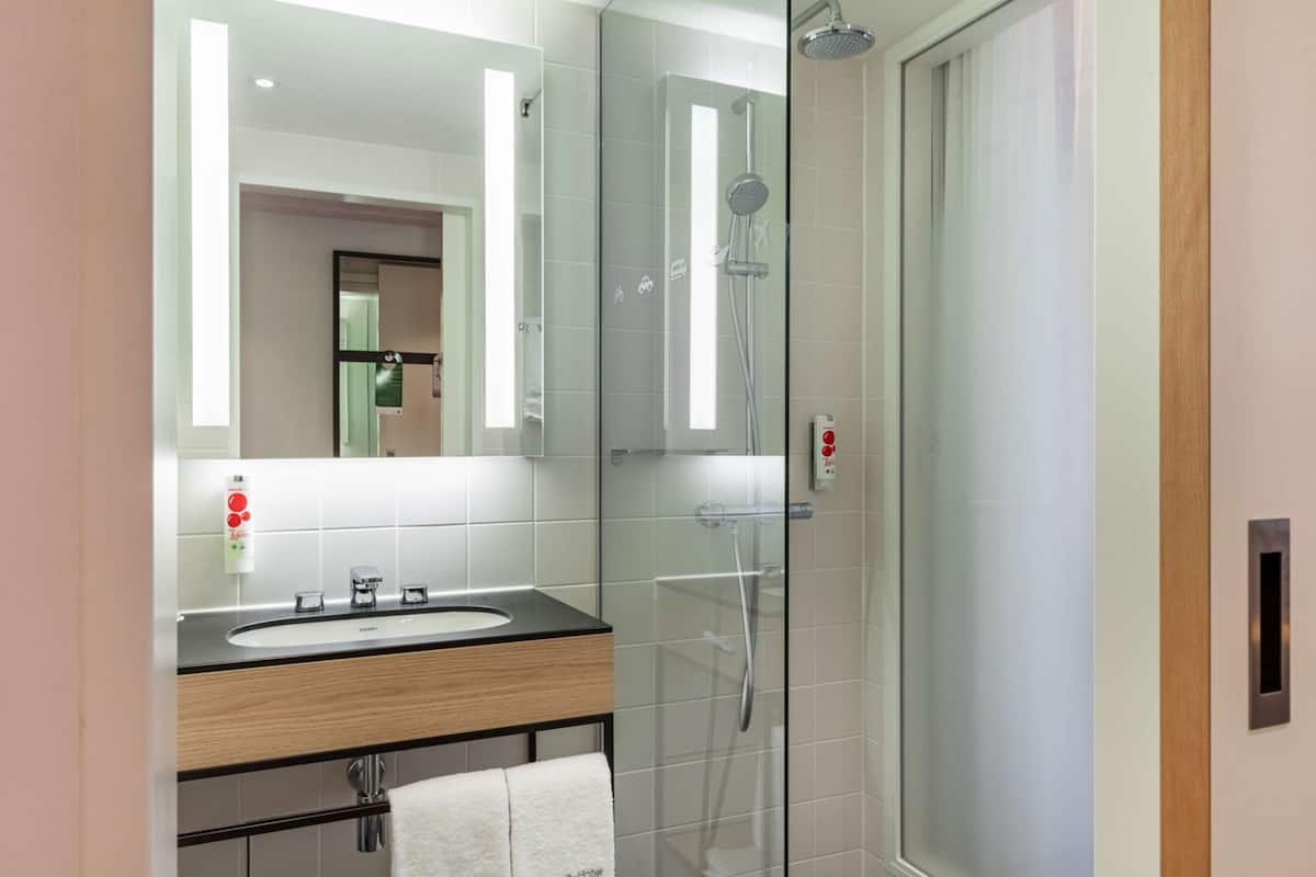 A modern bathroom with a glass-enclosed shower, a wooden vanity with a sink, and a mirror above the vanity.
