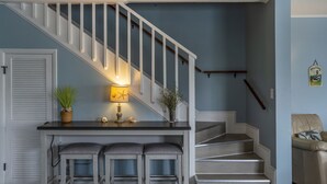Eine Treppe mit weißen Geländern, ein dunkles Holztisch mit zwei Stühlen und einer Lampe.