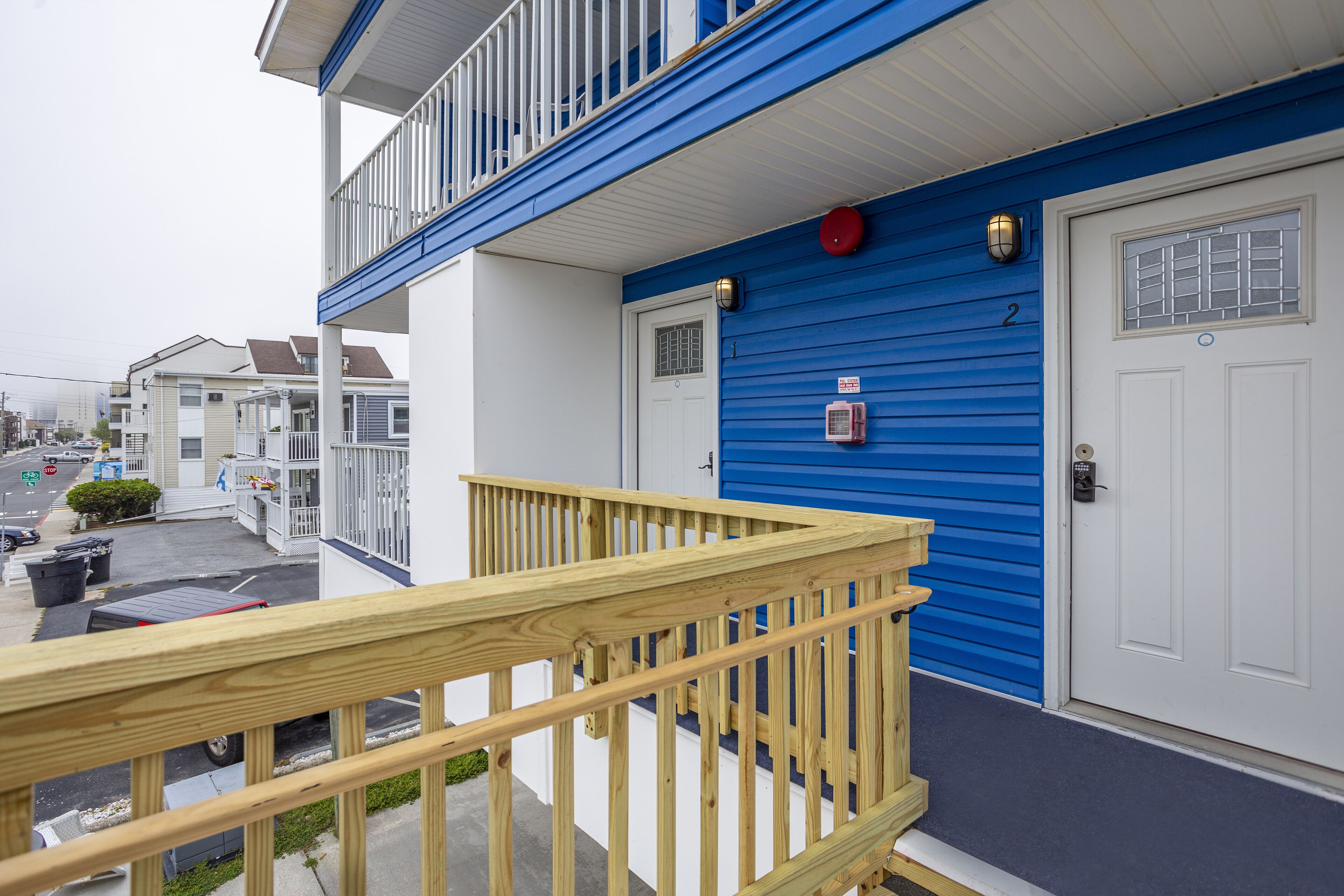 A residential building with a blue exterior, a white door, and a wooden balcony railing.