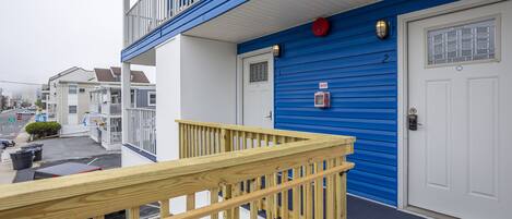 A residential building with a blue exterior, a white door, and a wooden balcony railing.