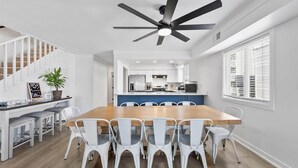 Eine moderne Küche mit weißen Schränken, einer zentralen Kochinsel und einem Deckenventilator.