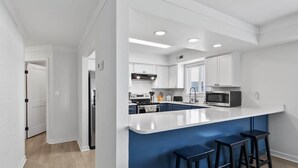 Eine moderne Küche mit weißen Schränken, einer blauen Kochinsel und einem Edelstahl-Kühlschrank.
