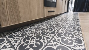 Un couloir avec des carreaux noirs et blancs formant un motif, des armoires en bois et une porte noire.