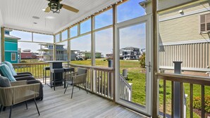 Une terrasse extérieure couverte, aménagée avec des meubles en osier et dotée d’un ventilateur de plafond.