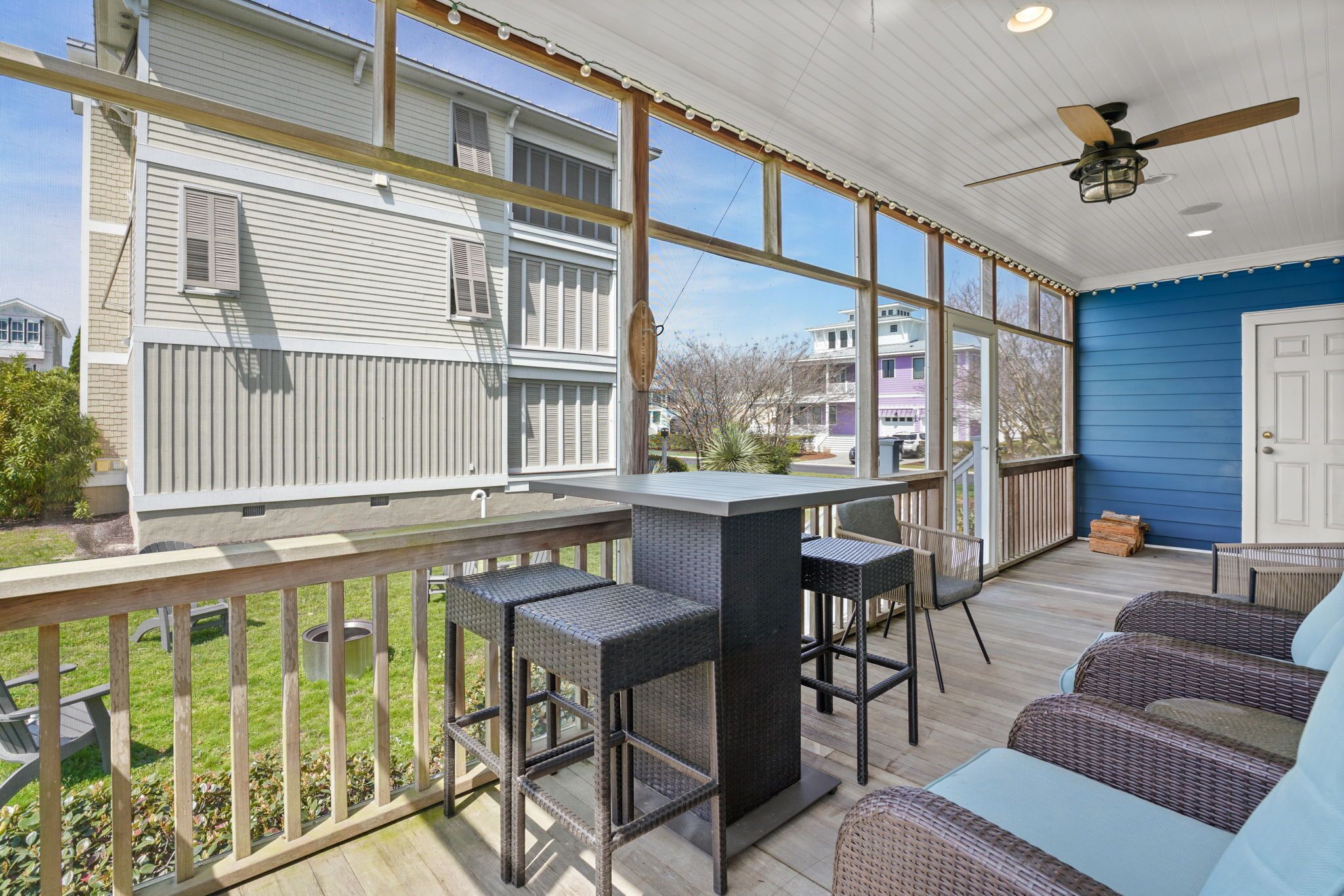 A covered outdoor area with a bar, seating, and a view of neighboring houses.