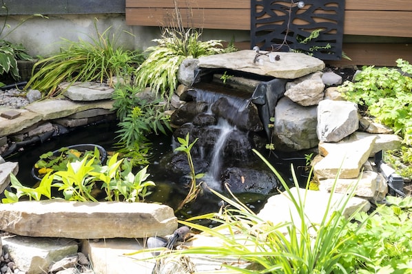 A small waterfall in a garden with rocks and plants.