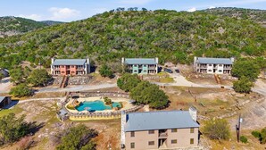 Un complexe hôtelier comprenant trois bâtiments, une piscine et un paysage vallonné en arrière-plan.