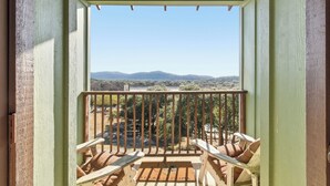 Un balcon avec des chaises en bois, une vue sur les montagnes et un ciel dégagé.