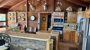 A rustic kitchen with wooden cabinets, a granite countertop, a stainless steel refrigerator, and a microwave. - 🤩 Charming Lake Side Retreat perched above scenic Faubush Creek.  (Nancy)