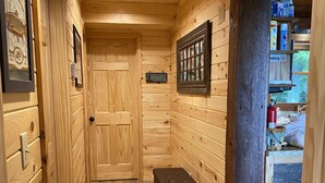 A wooden hallway with a door labeled "Welcome to the Lake," a small black ottoman, and a shelf with a "No Smoking" sign. - 🤩 Charming Lake Side Retreat perched above scenic Faubush Creek.  (Nancy)