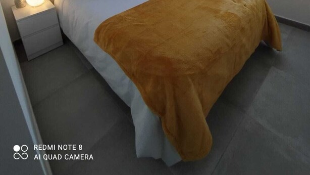 Ein Schlafzimmer mit Bett, Nachttischen, einer Nachttischlampe und einem Fenster.