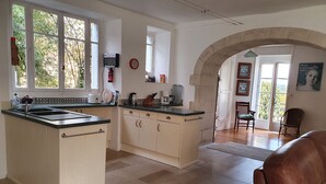 A spacious kitchen with a central island, large windows, and an arched doorway leading to a dining area.