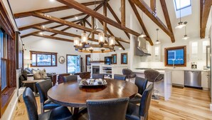 A spacious dining area with a wooden table and leather chairs, a kitchen with modern appliances, and a high ceiling with exposed beams. - BEST Ski In/Out location in the heart of Park City!  Updated, clean and stocked. (PARK CITY)