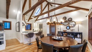 A spacious dining area with a wooden table and chairs, a kitchen in the background, and exposed wooden beams on the ceiling. - BEST Ski In/Out location in the heart of Park City!  Updated, clean and stocked. (PARK CITY)