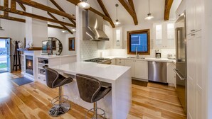 A modern kitchen with a central island, bar stools, stainless steel appliances, and exposed wooden beams. - BEST Ski In/Out location in the heart of Park City!  Updated, clean and stocked. (PARK CITY)