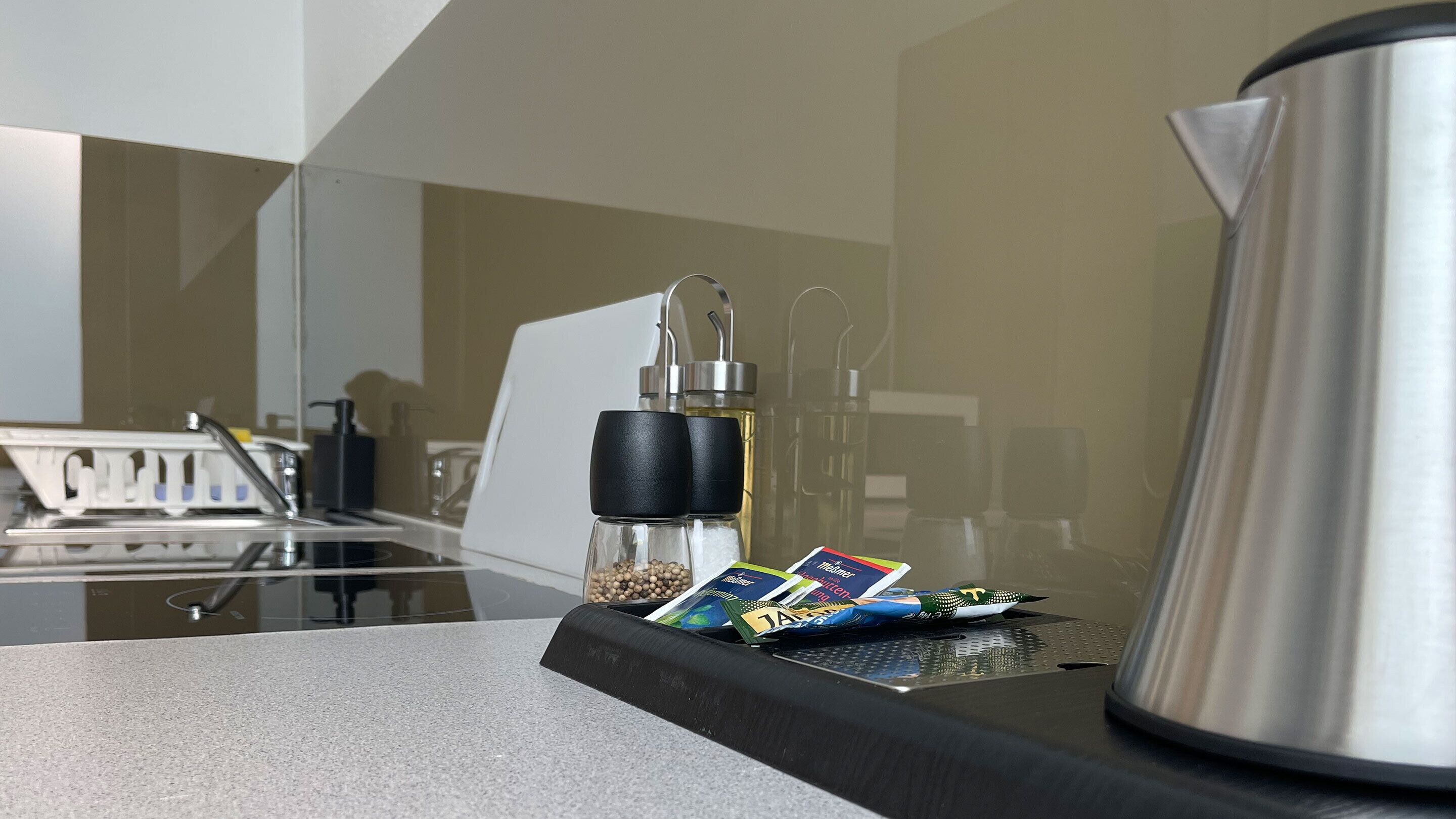 A kitchen counter with a coffee maker, salt and pepper shakers, and a spice rack with packets.