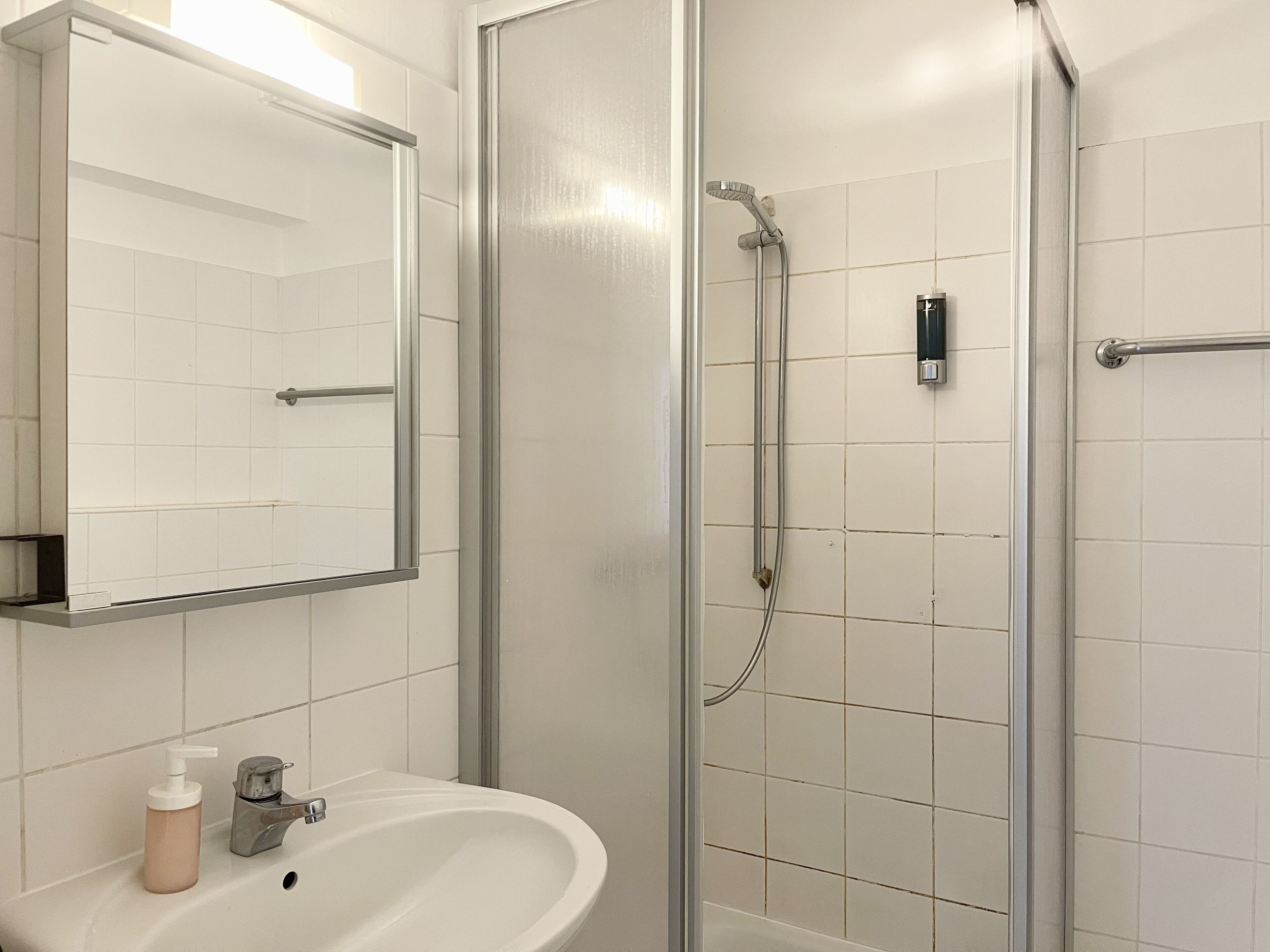 Ein Badezimmer mit Waschbecken, Spiegel und Dusche.