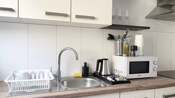 A modern kitchen with a stainless steel sink, a microwave, and a dish rack.
