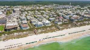 Vista aérea de una zona residencial costera con casas, una playa y un faro.