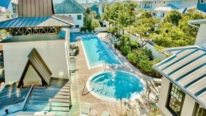 Un hotel con piscina, sillones de descanso y vistas a otros edificios.