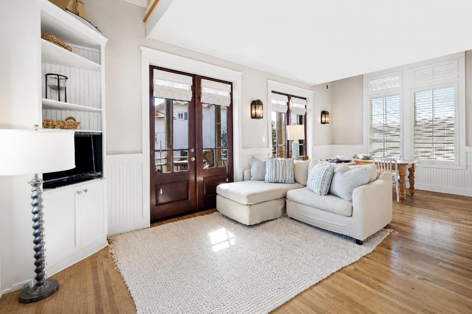 A modern living room with a sectional sofa, a white rug, and a wooden floor.