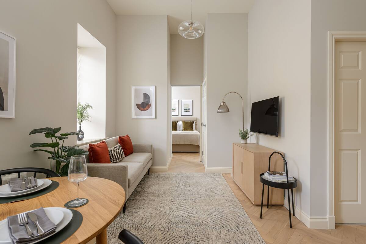 Ein modernes Wohnzimmer mit Essbereich, einer Couch, einem Fernseher und einer Pflanze.