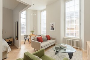A modern living room with a sofa, a glass coffee table, and a dining area with a table and chairs.