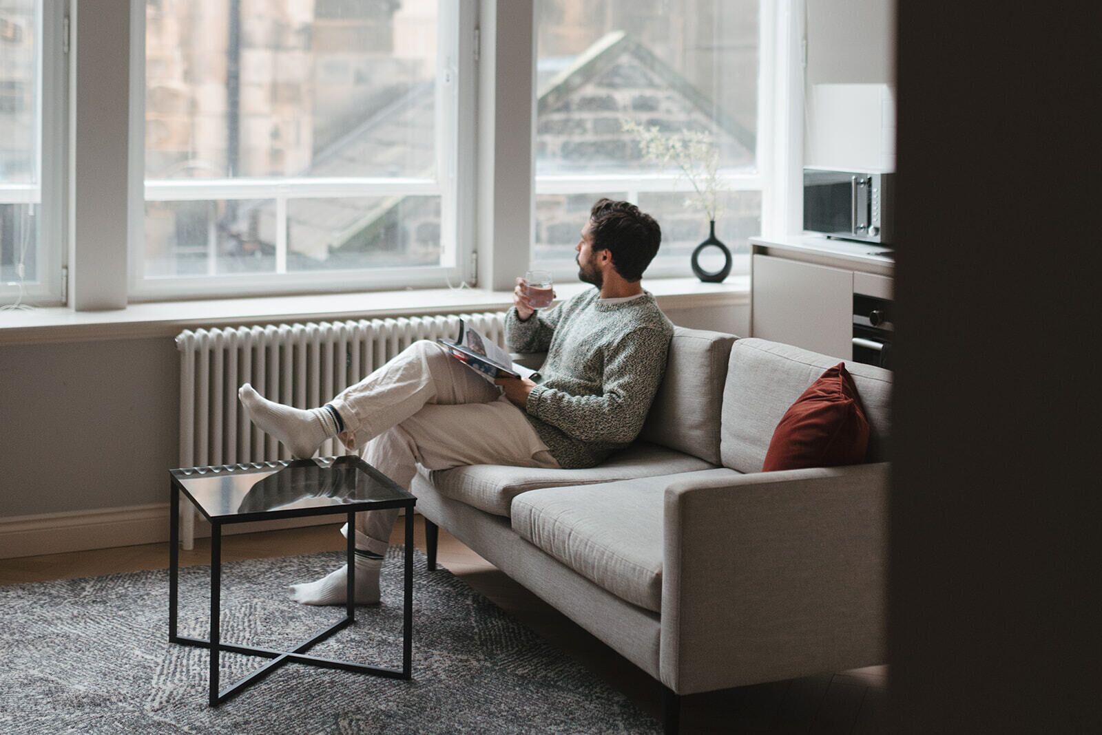 A person sitting on a sofa with a book, a coffee cup, and a smartphone.