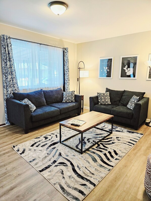 A modern living room with two sofas, a coffee table, and a floor lamp.