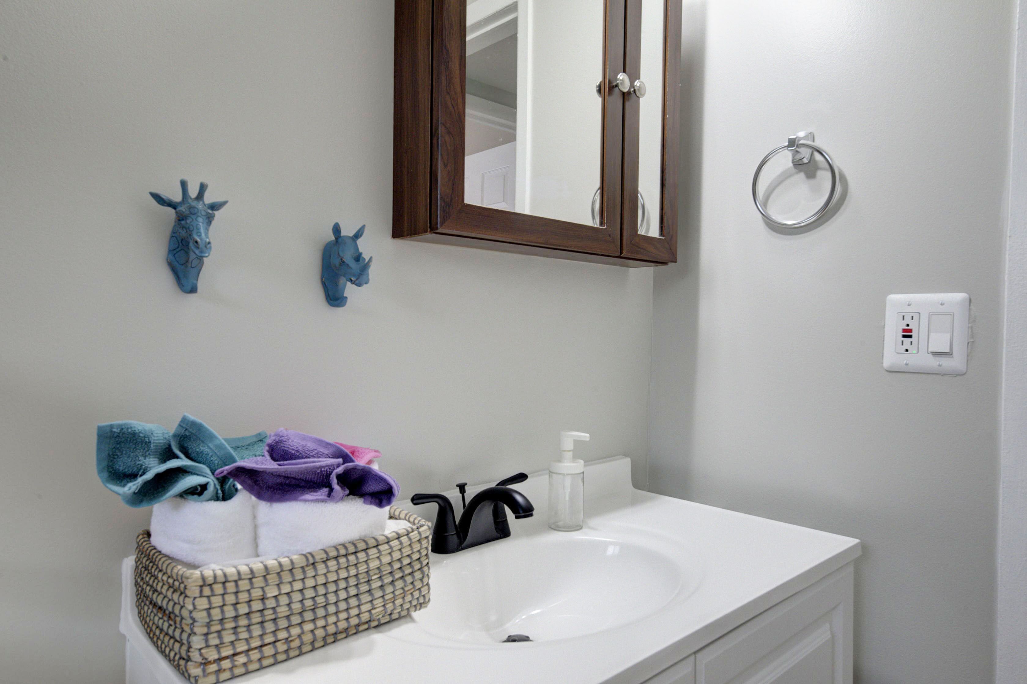 Un baño con un lavabo blanco, un espejo y dos adornos azules en la pared.