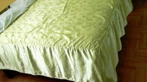 A bed with a green patterned bedspread and white pillows. - Puriq wasi (Socabaya)