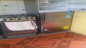 A kitchen with a gas stove and a stainless steel refrigerator. - Puriq wasi (Socabaya)