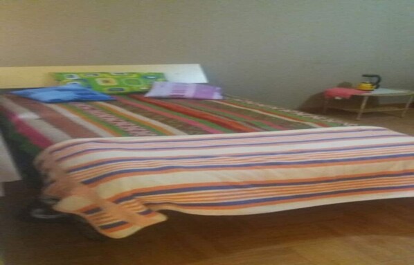 A bed with a striped blanket, a pillow, and a book on a wooden floor.