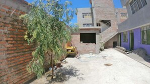 A courtyard with a brick wall, a tree, and a partially constructed building with a staircase. - Puriq wasi (Socabaya)