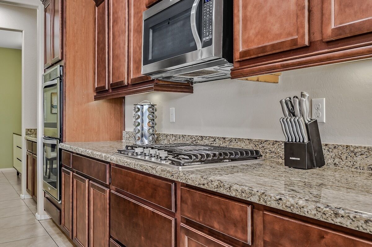 A kitchen with wooden cabinets, a stainless steel microwave, a gas stove, and a knife block.