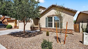 Ein Wohnhaus mit Steinverkleidung, einer Garage und einem gepflegten Garten mit Kies und kleinen Pflanzen.