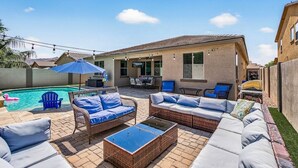 Ein Garten mit Swimmingpool, Gartenmöbeln und einer überdachten Terrasse.