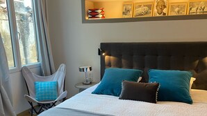 A modern bedroom with a large bed, a bedside table with a lamp, a chair, and a window with curtains. - Flamingo Duplex, historical centre, l'Hauture, Arles (Arles)