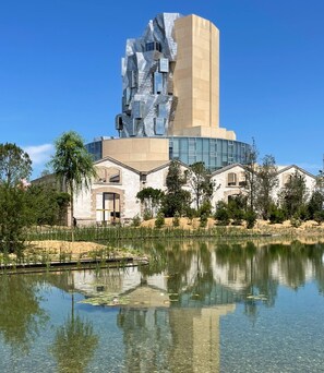 A modern building with a unique angular design, a central courtyard, and a reflective water feature. - Flamingo Duplex, historical centre, l'Hauture, Arles (Arles)