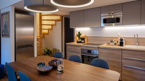 A modern kitchen with a built-in oven, a microwave, and a sink. There is a dining table with chairs and a vase with flowers. - Flamingo Duplex, historical centre, l'Hauture, Arles (Arles)