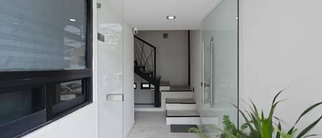 Un intérieur moderne avec une porte en verre, un escalier et une plante en pot.