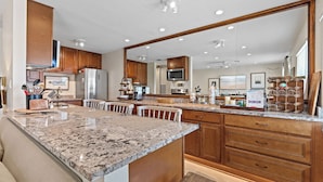 A modern kitchen with granite countertops, wooden cabinets, and a large island with seating.