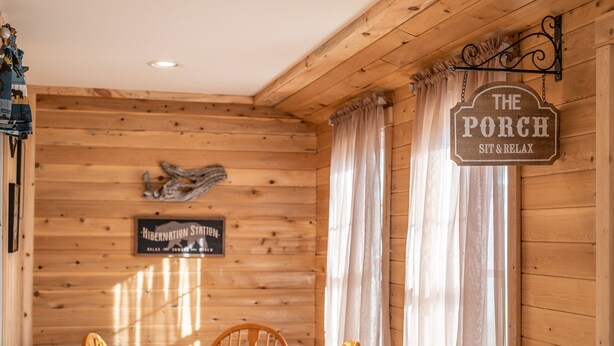 Un intérieur en bois avec une enseigne indiquant : « Le Porche : asseyez-vous et détendez-vous ».