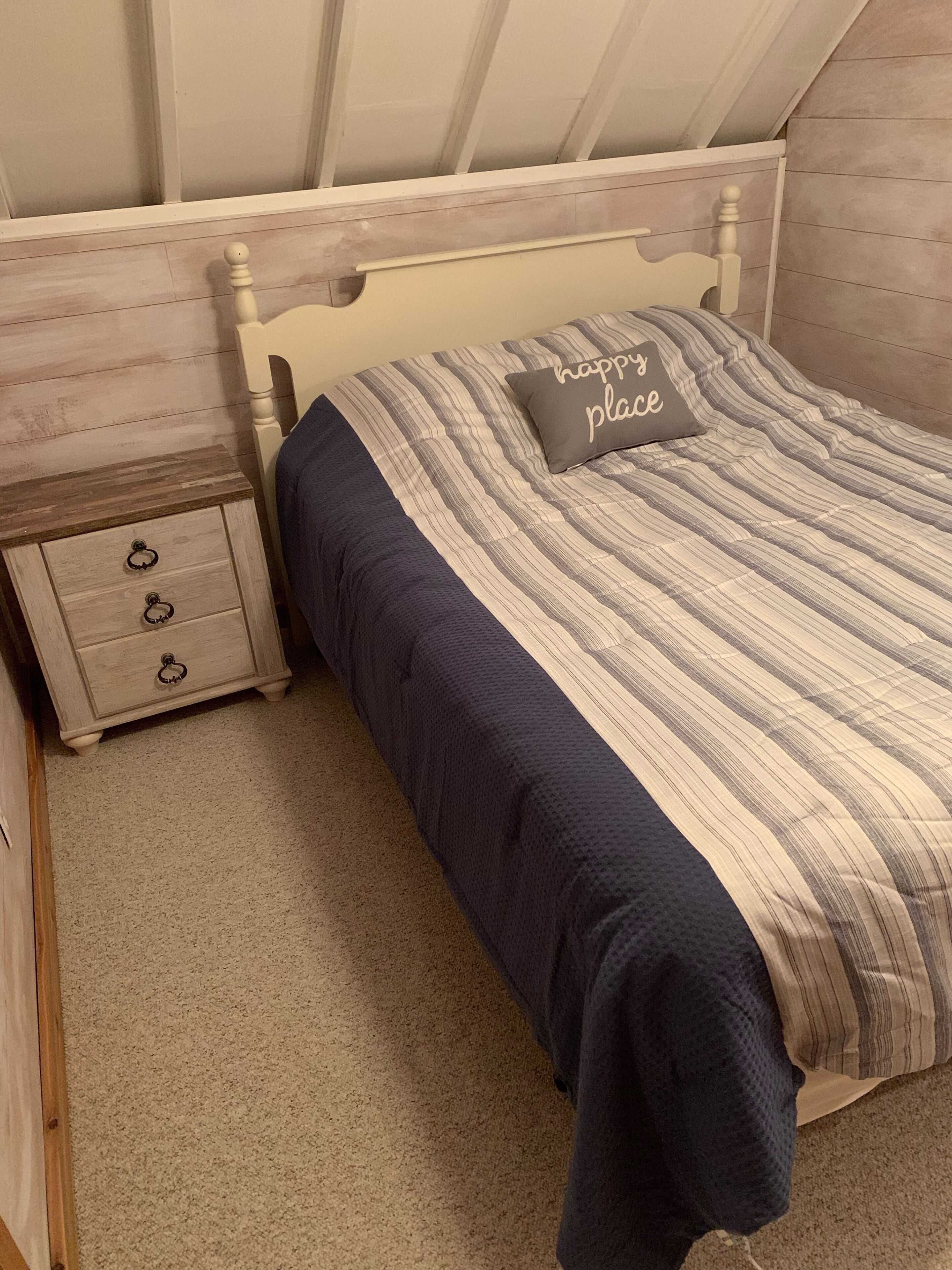 Un dormitorio con una cama, una mesita de noche y una cómoda.