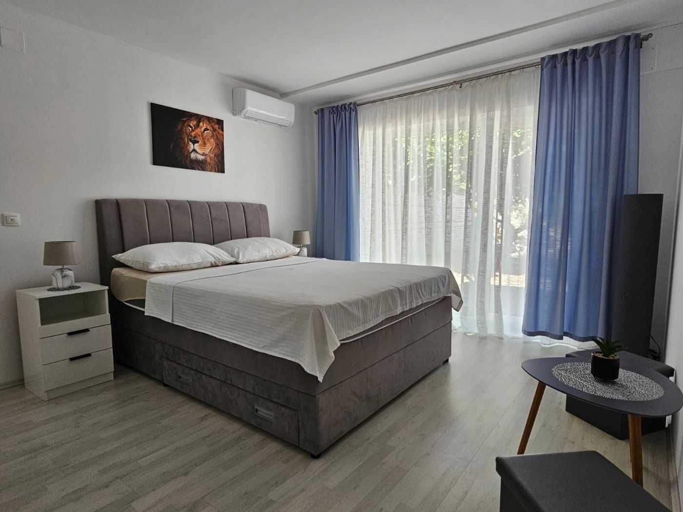 A modern bedroom with a bed, bedside tables, a TV, and a window with curtains.